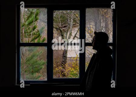 Silhouette eines Mannes, der von hinten vor einem zerbrochenen Fenster erschossen wurde Stockfoto