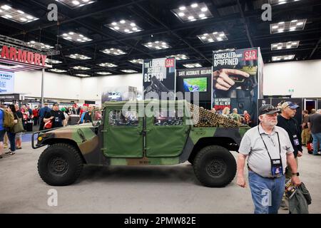 Indianapolis, Usa. 15. April 2023. Gäste gehen während der jährlichen Tagungen und Ausstellungen der National Rifle Association im Indiana Convention Center in Indianapolis an einem Humvee vorbei, der an einem Stand geparkt ist. Das Forum ist Teil der jährlichen Tagungen und Ausstellungen der National Rifle Association, die voraussichtlich rund 70.000 Gäste anziehen werden. Heute geöffnet und bis Sonntag geöffnet. Kredit: SOPA Images Limited/Alamy Live News Stockfoto