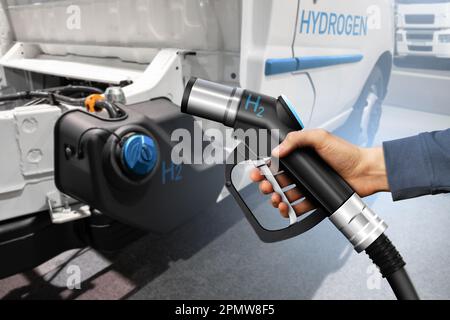 Hand mit H2-Tankdüse auf einem Hintergrund eines Wasserstoff-Brennstoffzellenladers. Umweltfreundliches Nutzfahrzeugkonzept. Hochwertiges Foto Stockfoto