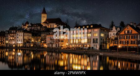 Die wunderschöne Stadt Thun mit den Reflexionen der Gebäude im Fluss Aare bei Nacht Stockfoto
