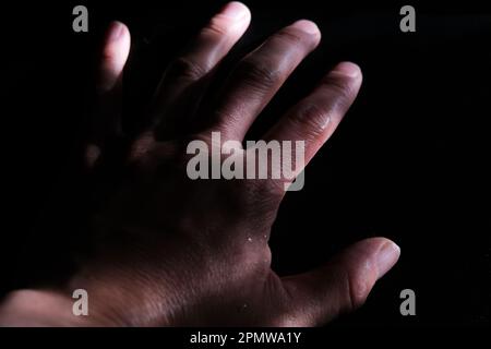 Nahaufnahme der Hand eines Menschen im dunklen Hintergrund. Stockfoto
