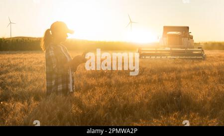 Landwirt mit digitalem Tablet im Hintergrund der Erntemaschine. Konzept der intelligenten Landwirtschaft. Hochwertiges Foto Stockfoto
