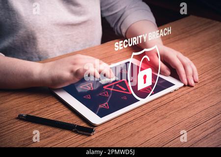 Frau, die ein digitales Tablet benutzt, mit einer Warnung vor Systembruch auf dem Bildschirm. Unternehmenstechnologie für Datenschutz im Bereich Cyber-Sicherheit. Stockfoto