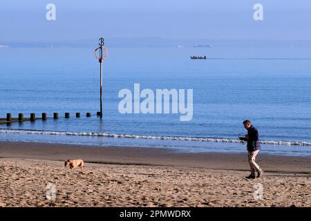 Edinburgh, Schottland, Großbritannien. 15. April 2023 Einige Aktivitäten am frühen Morgen am Strand von Portobello mit Menschen, die den milden Start in den Tag mit blauem Himmel und Sonnenschein genießen. Mit dem Hund am Strand entlang mit einem Ruderboot in der Flussmündung. Kredit: Craig Brown/Alamy Live News Stockfoto