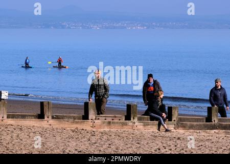 Edinburgh, Schottland, Großbritannien. 15. April 2023 Einige Aktivitäten am frühen Morgen am Strand von Portobello mit Menschen, die den milden Start in den Tag mit blauem Himmel und Sonnenschein genießen. Spaziergang am Strand mit Paddelboardern in der Mündung. Blick in Richtung Dalgety Bay Fife. Kredit: Craig Brown/Alamy Live News Stockfoto