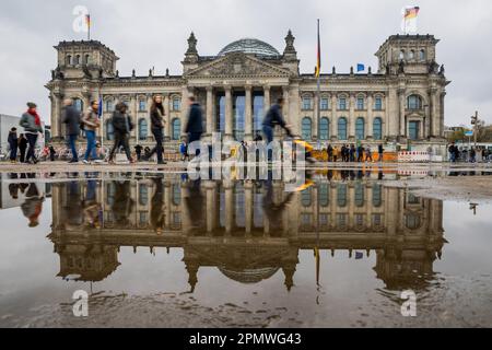 Berlin, Deutschland. 15. April 2023. Vor dem Reichstagsgebäude laufen die Menschen zwischen den Pfützen. Kredit: Christoph Soeder/dpa/Alamy Live News Stockfoto