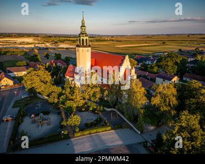 Blick aus der Vogelperspektive auf eine malerische ländliche Stadt in der Dämmerung, die von der untergehenden Sonne und üppigen Bäumen umgeben ist Stockfoto