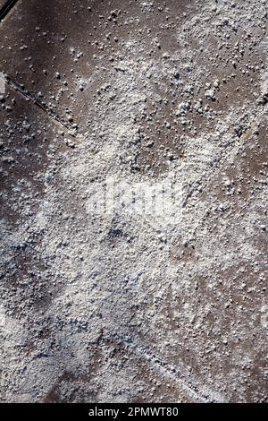 Nahaufnahme der salzbedeckten Struktur des Gehwegs. Städtische Umwelt und Sicherheit. Salz auf eiskaltem Pflaster in der Stadt. Stockfoto