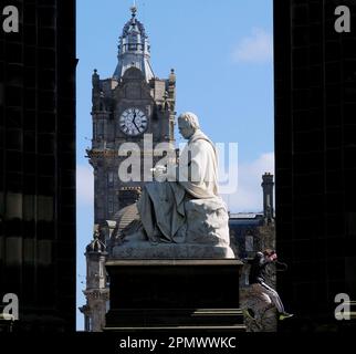 Edinburgh, Schottland, Großbritannien. 15. April 2023 Sonniger und klarer blauer Himmel über der Stadt und den East Princes Street Gardens mit abenteuerlustigen Kindern, die über das Walter Scott Monument und die Statue klettern. Kredit: Craig Brown/Alamy Live News Stockfoto