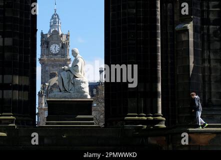 Edinburgh, Schottland, Großbritannien. 15. April 2023 Sonniger und klarer blauer Himmel über der Stadt und den East Princes Street Gardens mit abenteuerlustigen Kindern, die über das Walter Scott Monument und die Statue klettern. Kredit: Craig Brown/Alamy Live News Stockfoto