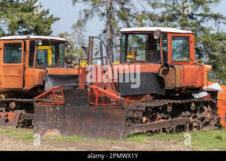 Ein alter Bulldozer an einem sonnigen Tag mit einem Eimer, um die Erde in einer verlassenen Fabrik zu bewegen. Ukraine, Europa Stockfoto