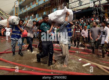 Dhaka. 15. April 2023. Die Menschen transportieren Waren von dem Standort, an dem am 15. April 2023 auf einem beliebten Bekleidungsmarkt in Dhaka, Bangladesch, ein massiver Brand ausbrach. Am Samstagmorgen brach hier das Feuer aus. Ershad Hossain, leitender Offizier der Feuerwehr und des Zivilverteidigungsamtes, sagte Xinhua, dass 30 Feuerwehrfahrzeuge das Feuer im großen „Neuen Supermarkt“ der Stadt bekämpften. Kredit: Xinhua/Alamy Live News Stockfoto