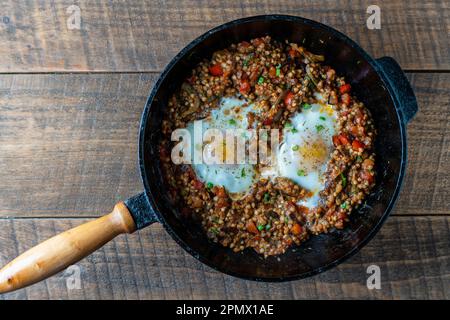 Gekochter Buchweizen mit Spiegeleiern, Paprika, Karotten und Zwiebeln, Nahaufnahme, Ukraine. Hintergrund für das Essen. Gesunde Ernährung Stockfoto