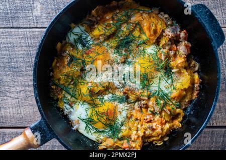 Gekochter Reis mit Spiegeleiern, Kürbis, Paprika, Karotten und Zwiebeln in einer gusseisernen Pfanne, Nahaufnahme. Lebensmittelhintergrund. Gesundes Essen Stockfoto