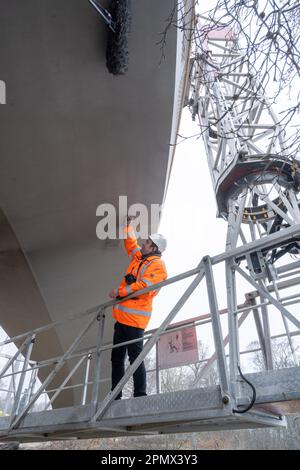 15. April 2023, Mecklenburg-Vorpommern, Sassnitz: Ronny Seidel, Ingenieur überprüft den neuen Königsweg am Königsstuhl auf der Insel Rügen von einem Kirschpflücker aus. Bevor Besucher die neue Aussichtsplattform über dem Königsstuhl auf der Insel Rügen ab dem nächsten Wochenende betreten können, wurden zunächst Experten nach DIN 1079 für den ersten Haupttest einberufen. In Zukunft können Besucher einen 185 Meter langen, ellipsenförmigen Rundweg entlang gehen, der von einem Stützmast gehalten wird, der über dem 118 Meter hohen Königsstuhl - der größten Kreide - hängt Stockfoto