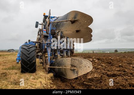 Ballinadee, West Cork, Irland. 15. April 2023. JJ Hayes pflügt an einem bedeckten und duschenden Tag mit einem New Holland T6,145-Traktor und einem New Holland-Umkehrpflug in der Nähe von Ballinadee, West Cork, ein Feld für Gerstenpflanzen. Kredit: AG News/Alamy Live News Stockfoto