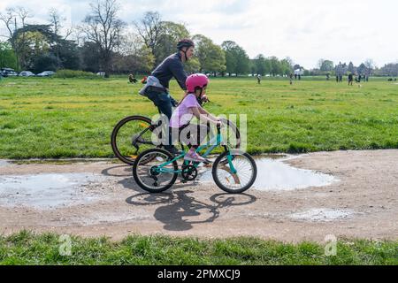 London, Großbritannien. 15. April 2023 Radfahrer fahren in der Nachmittagssonne auf dem Wimbledon Common im Südwesten Londons über Wasserflecken. Wettervorhersage prognostiziert steigende Temperaturen auf 20C °C nach dem nassesten im März seit 40 Jahren Kredit: amer Ghazzal/Alamy Live News Stockfoto