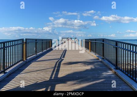 Ein langer Pier, der an einem warmen, sonnigen Tag ins Meer führt, am Holmes Beach auf Anna Maria Island, Florida Stockfoto