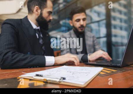 Geschäftsleute treffen sich im Freien. Zwei Männer benutzen einen Laptop. Arbeitspause. Team- und Business-Support. Zusammenarbeit und Partnerschaft Stockfoto