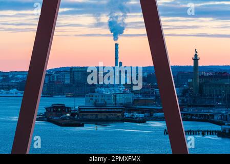 Die atemberaubende Skyline von Göteborg spiegelt sich im Morgengrauen des ruhigen Meeres wider, mit ihren herrschaftlich blauen Gebäuden, die sich vor einem wolkenreichen Himmel erheben. Stockfoto