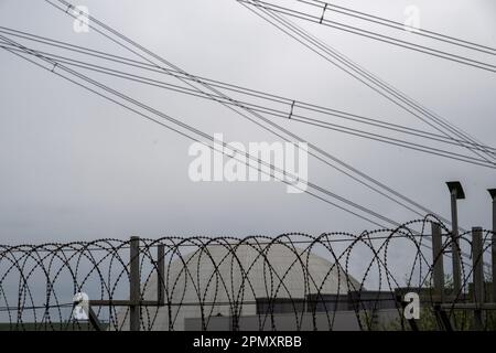 Neckarwestheim, Deutschland. 15. April 2023. Sturmleitungen aus dem Kernkraftwerk verlaufen hinter Stacheldraht. Die Trennung der Kernkraftwerke Isar 2, Neckarwestheim und Emsland vom Stromnetz am Samstag markierte das Ende der Ära der kommerziellen Stromerzeugung mit Kernkraftwerken in Deutschland. Kredit: Stefan Puchner/dpa/Alamy Live News Stockfoto