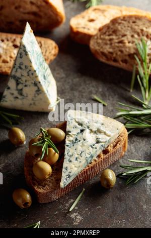 Blauschimmelkäse mit grünen Oliven, Rosmarin und frischem Brot. Stockfoto