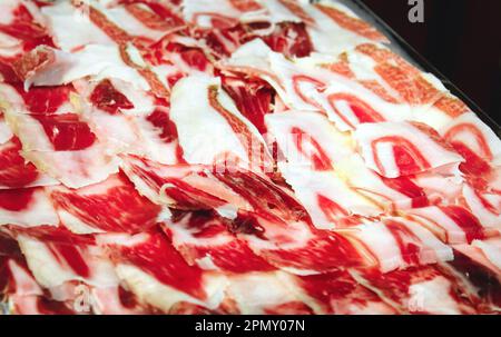 Ein Teller mit serrano aus Jamon, geräucherter spanischer Schinken, in dünne Scheiben geschnitten, auf einem Tablett Stockfoto