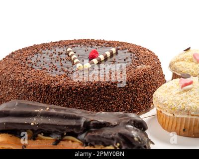 Schokoladenkuchen, Muffin und Eclairs auf weißem Hintergrund. Köstliche Süßigkeiten. Nahaufnahme. Stockfoto