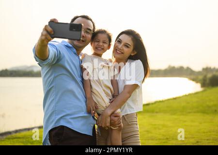 Familie macht Selfie-Fotos mit grüner Wiese und Blick auf den Fluss Stockfoto