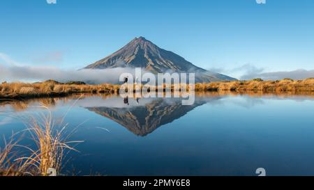 Ein paar Wanderungen auf der Pouakai-Strecke. Der Taranaki spiegelte sich im tarn in der Morgensonne wider. Neuseeland. Stockfoto