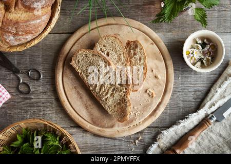 Scheiben Sauerteigbrot mit Goutweed, Gänseblümchen und Nesseln - wilde essbare Pflanzen Stockfoto