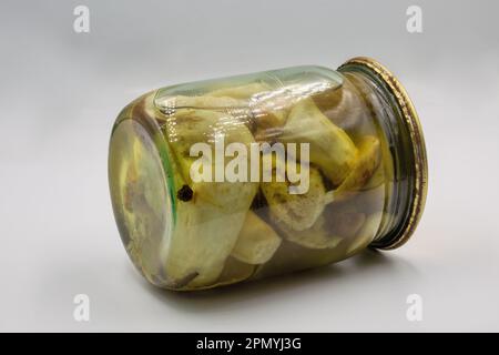 Glasglas mit hausgemachten marinierten Porcini-Pilzen, geschlossen auf Weiß. Stockfoto