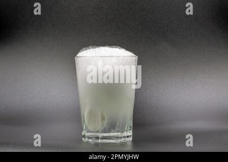 Auflösen von Brausetabletten in einem Glas mit Wassernaht auf Schwarz Stockfoto