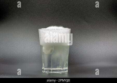 Auflösen von Brausetabletten in einem Glas mit Wassernaht auf Schwarz Stockfoto