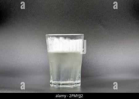 Auflösen von Brausetabletten in einem Glas mit Wassernaht auf Schwarz Stockfoto