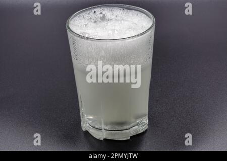 Auflösen von Brausetabletten in einem Glas mit Wassernaht auf Schwarz Stockfoto