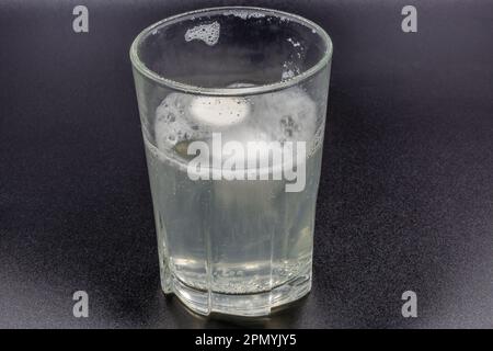 Auflösen von Brausetabletten in einem Glas mit Wassernaht auf Schwarz Stockfoto