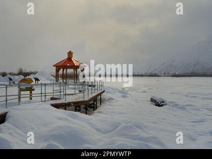 Roter Pavillon auf weißem verschneitem Feld an einem bewölkten Tag. Stockfoto