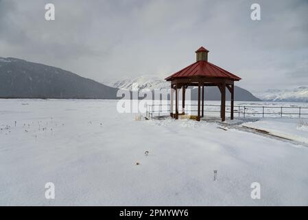 Roter Pavillon auf weißem verschneitem Feld an einem bewölkten Tag. Stockfoto