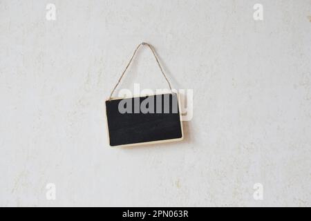 Kleine leere Schiefertafel mit Schnur hängen an Nagel Stockfoto