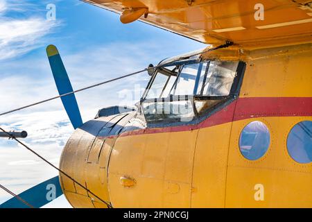 Cockpit eines alten, gelb bemalten Flugzeugs mit blauem Himmel im Hintergrund Stockfoto