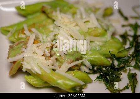 Italienische Küche, frische hausgemachte Pasta aus grünem Brokkoli und Penne mit Parmesan Parmigiano reggiano Käse Sauce mit getrocknetem Rucolasalat auf weißem Eber Stockfoto