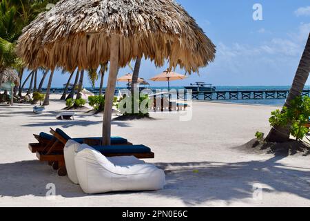 Komfortabler Strand und Liegestühle unter einer Palapa an einem sonnigen Tag am Strand in San Pedro, Ambergris Caye, Belize, Karibik. Stockfoto