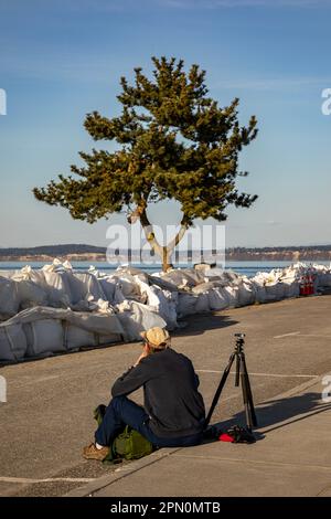 WA23334-05...WASHINGTON - Fotograf Tom Kirkendall, der auf den Sonnenuntergang wartet, um den Point No Point Leuchtturm zu fotografieren. Stockfoto