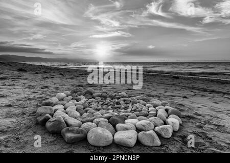 Während des Sonnenuntergangs am Strand werden heilige Ritualsteine für spirituelle Zeremonien in Einem Kreis angeordnet Stockfoto