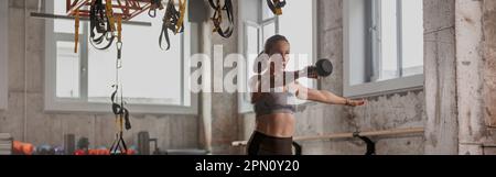 Athletische Frau, die im Fitnessstudio mit einer Kettlebell arbeitet Stockfoto