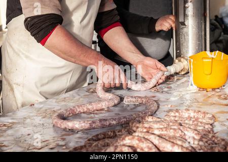 Bild von Menschen in Serbien, die Würstchen manuell zubereiten, mit einer Fleischzerkleinerungsmaschine, einer Wurstmaschine, die darauf spezialisiert ist, Fleisch zu Wurst zuzubereiten und zu verarbeiten. Stockfoto