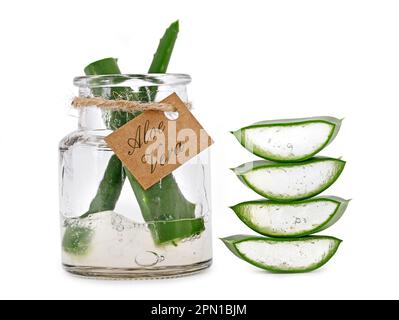 Glasgefäß mit dem Wort Aloe Vera gefüllt mit Aloe Vera Gel neben frisch geschnittenen Aloe Vera Blättern isoliert auf weißem Hintergrund Stockfoto