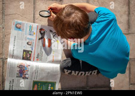 Junge brennt Zeitung mit Lupe Stockfoto