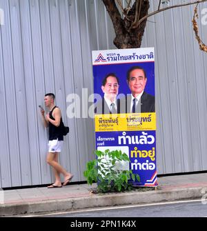 Ein Wahlkandidat benutzt ein Plakat an Straßenmöbeln, um sich bei potenziellen Wählern im Silom District, im Zentrum von Bangkok, Thailand, Südostasien zu bewerben. Nach der Auflösung des 25. Repräsentantenhauses am 20. März 2023 werden in Thailand am 14. Mai 2023 allgemeine Wahlen stattfinden. Ein Mann geht an einem Wahlplakat vorbei. Stockfoto